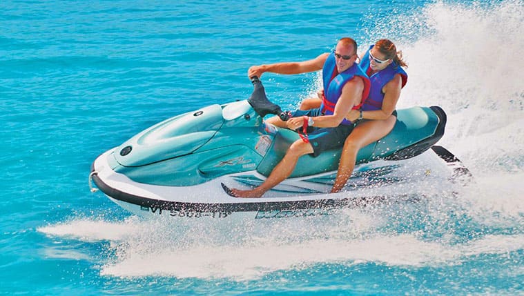 a couple riding a jet ski on the water at the beach